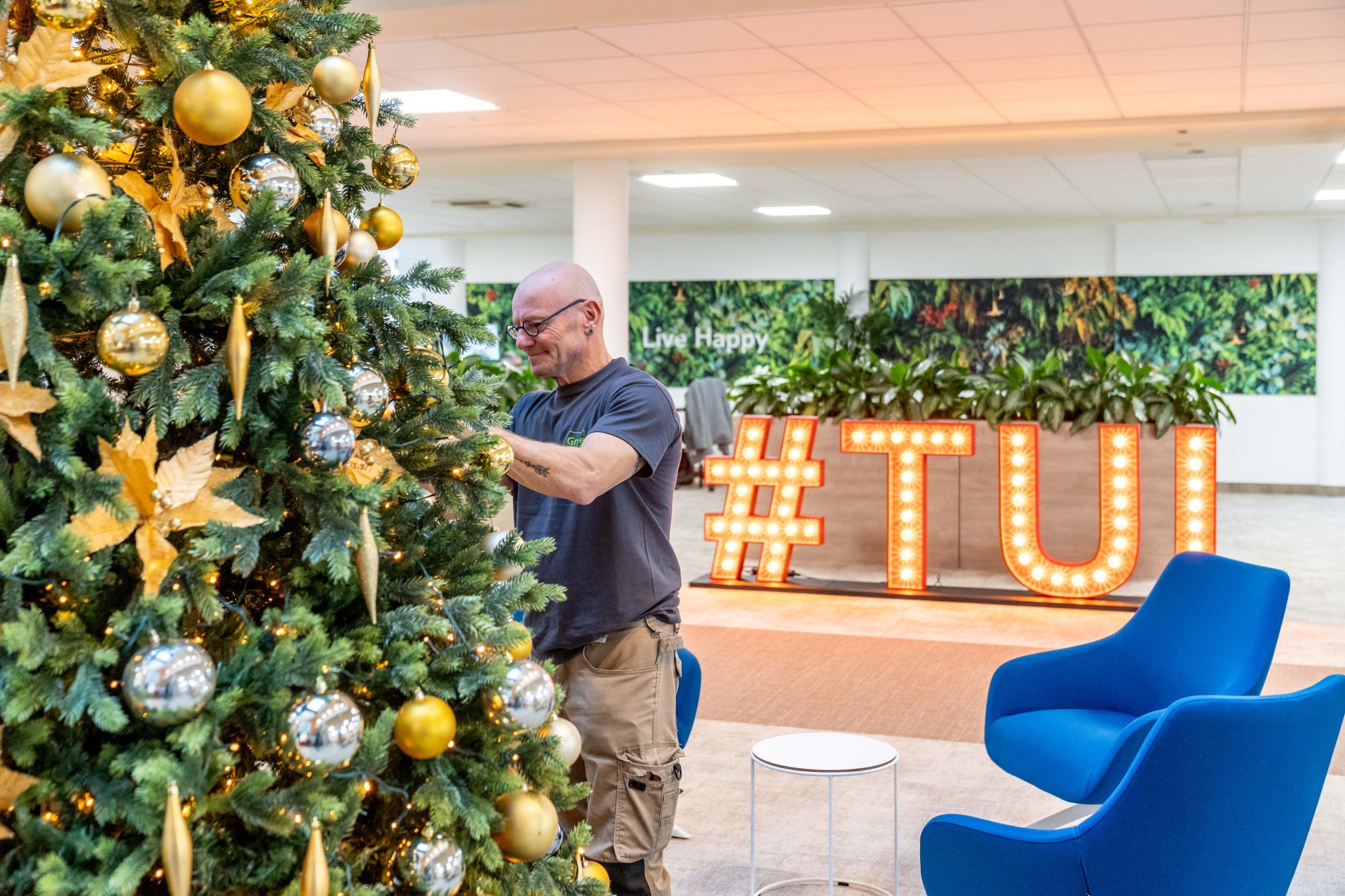 medewerker Green at the Office versiert kerstboom - Collaborateur Green at the Office décore un sapin de Noël