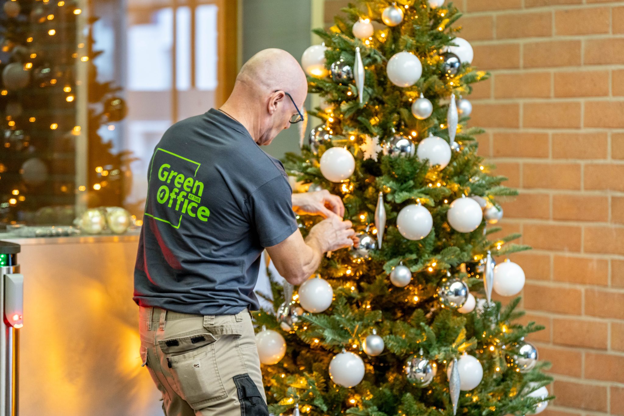 medewerker versiert kerstboom - Collaborateur décore un sapin de Noël